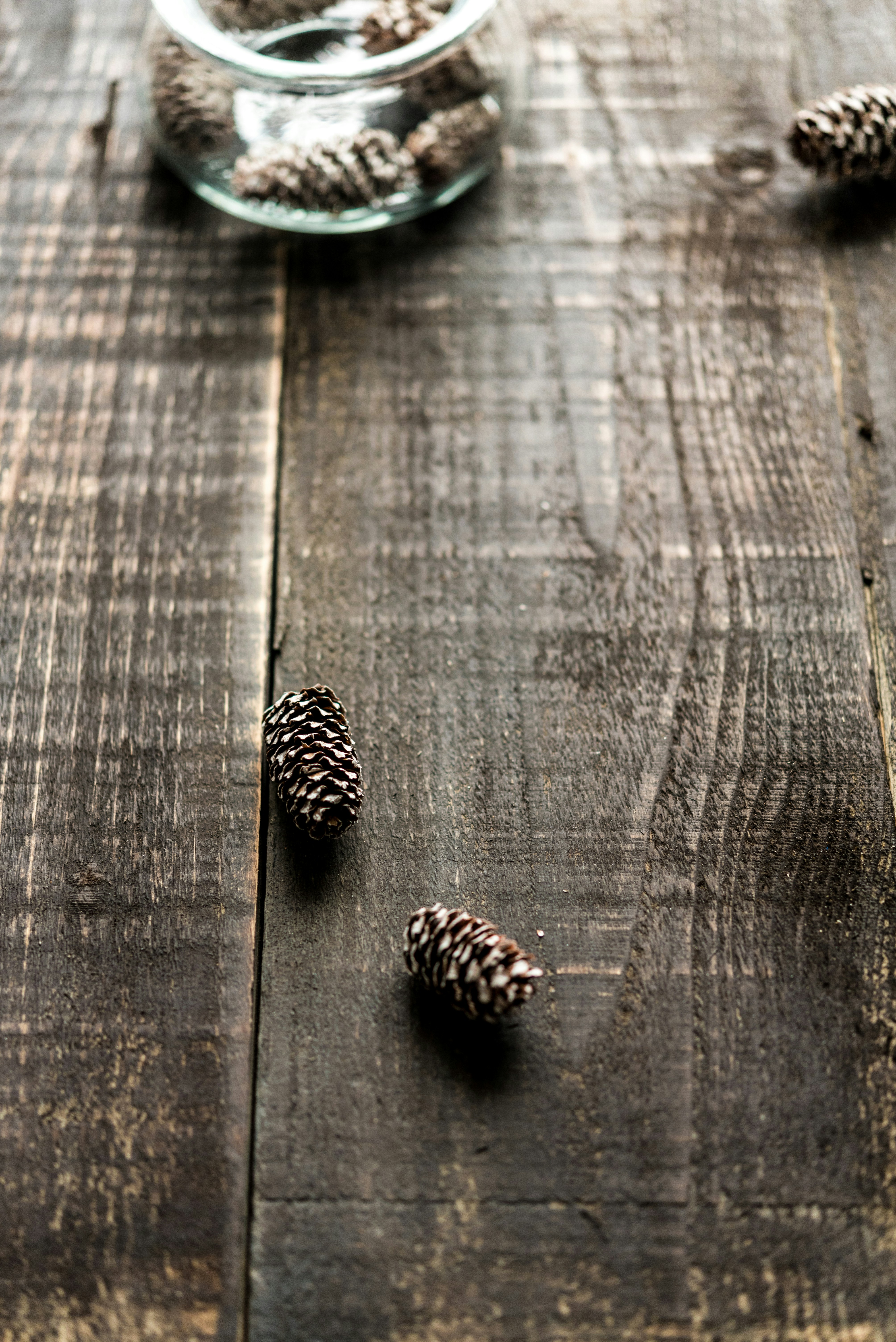 a glass bowl filled with pine cones on top of a wooden table