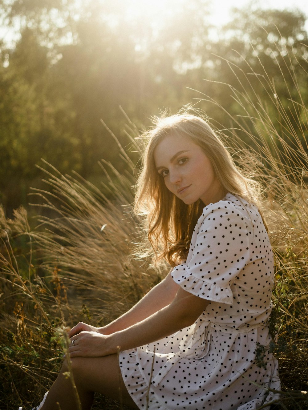 a woman sitting in a field of tall grass