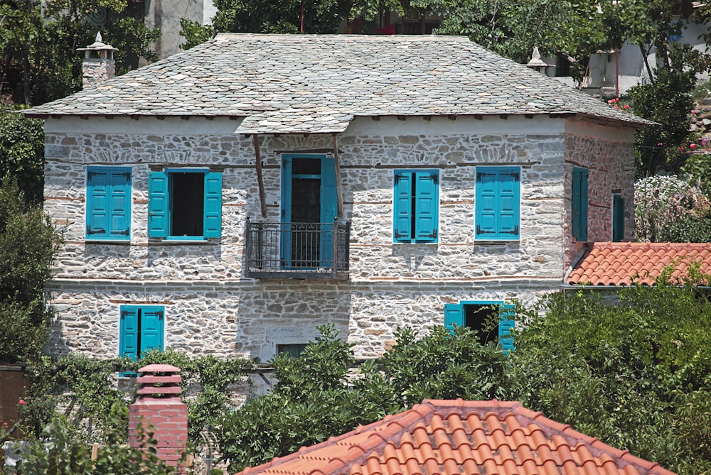 a stone house with blue shutters and a red roof