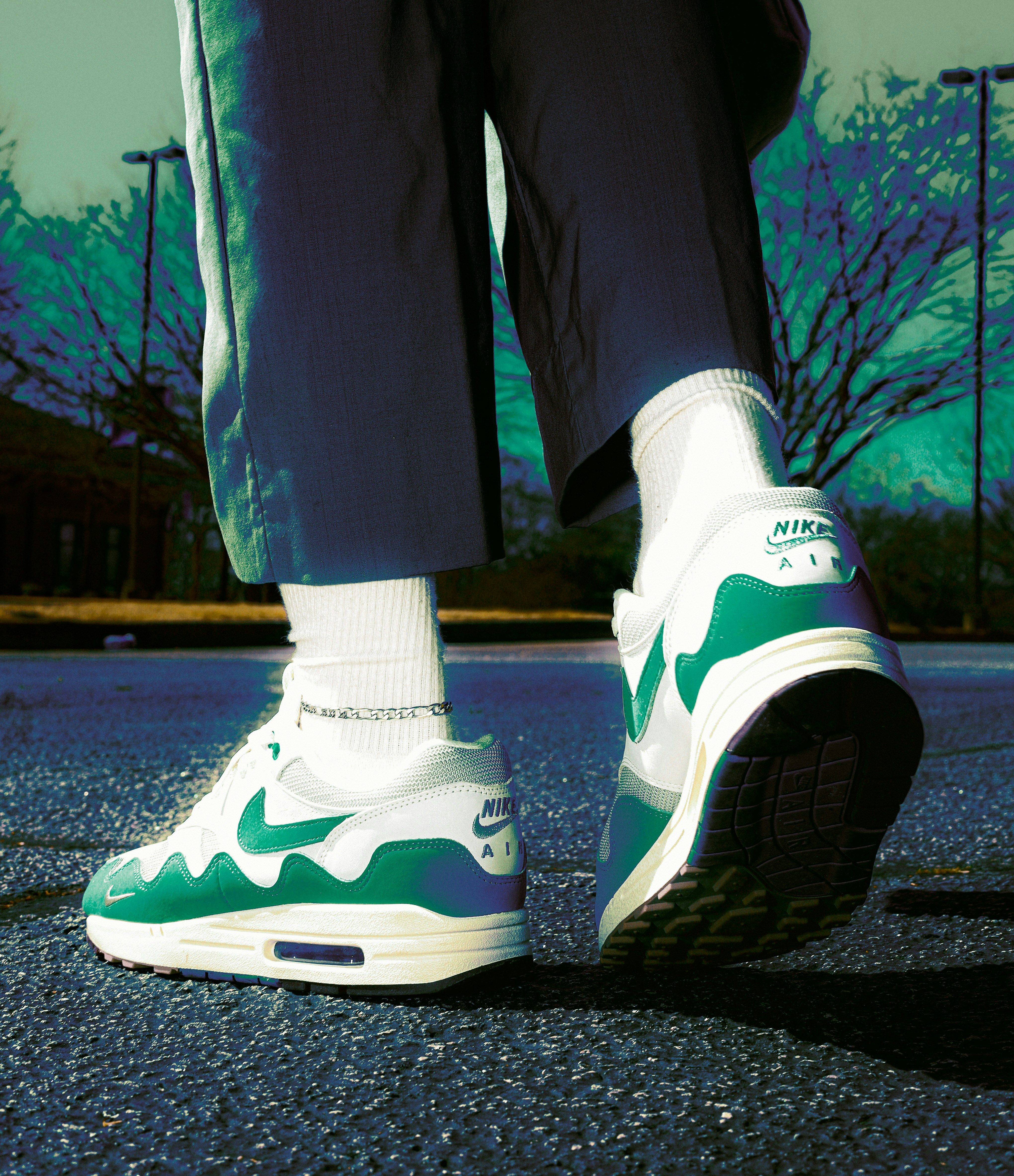 A person wearing green and white shoes standing on a street photo