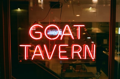 a red neon sign that reads goat tavern