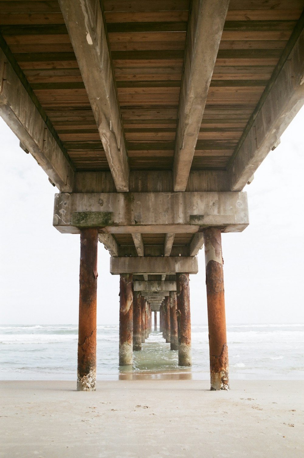 the underside of a wooden pier on a beach