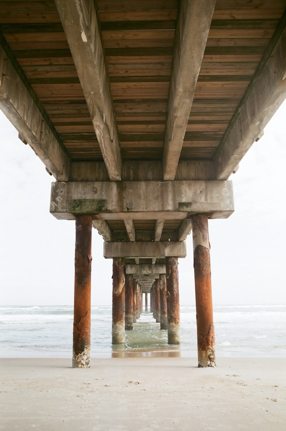 La parte inferiore di un molo di legno su una spiaggia