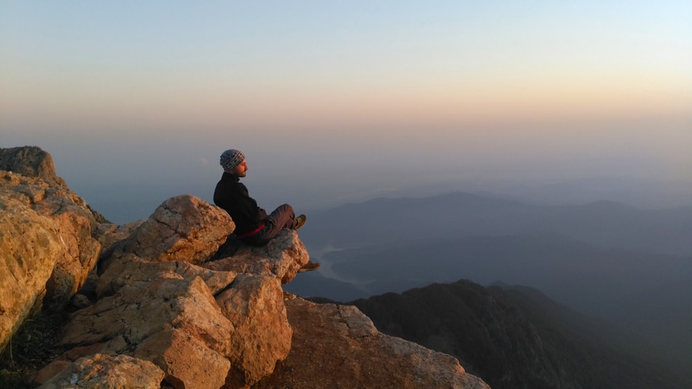 a person sitting on top of a large rock