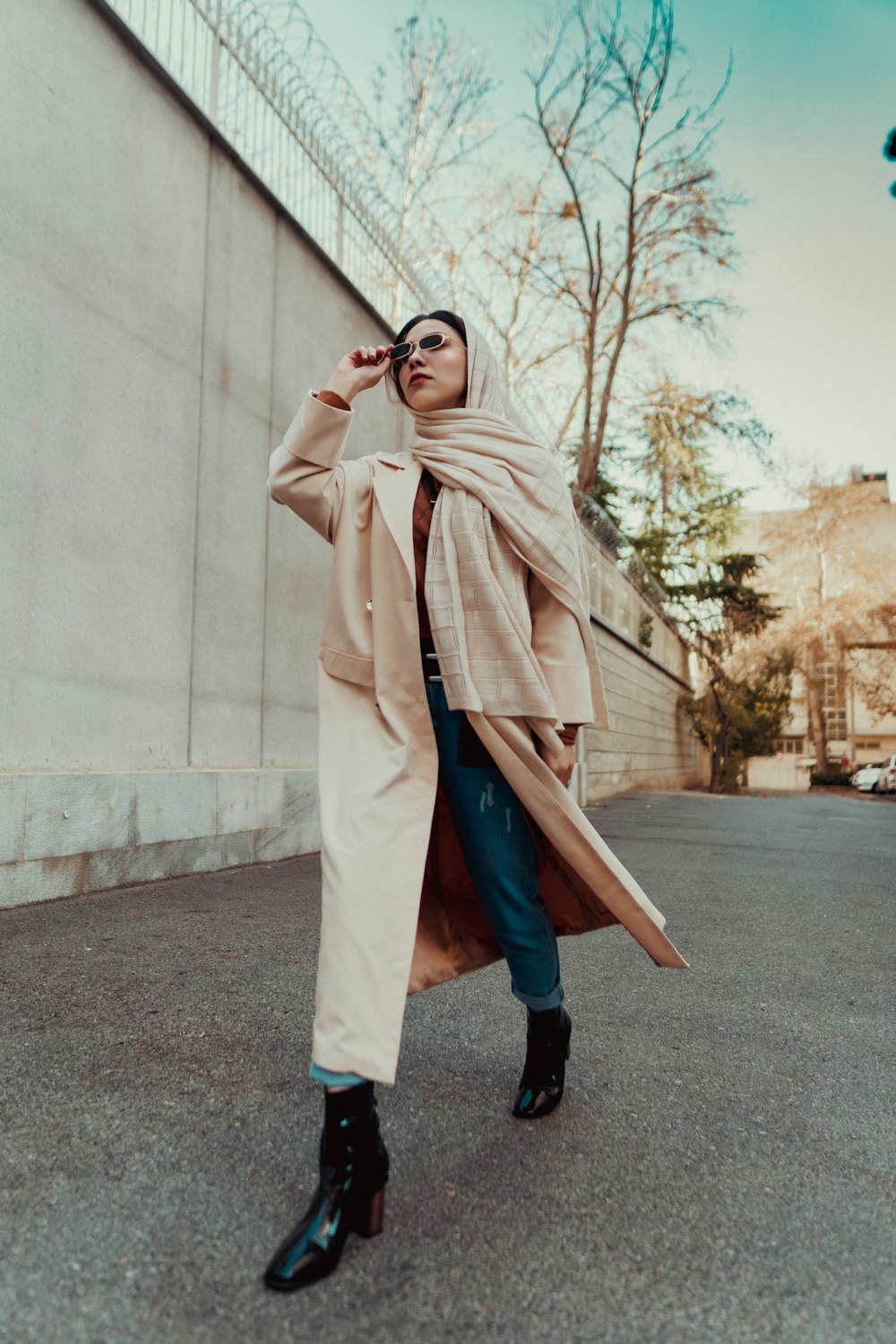 a woman in a trench coat is talking on a cell phone