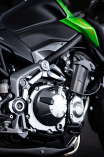 Close-up of a motorcycle engine showcasing mechanical parts with metallic finishes. The frame is sleek, emphasizing modern engineering with a touch of green detailing on the body.