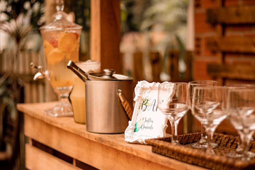 a wooden table topped with glasses and a pot