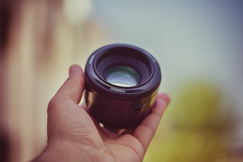 a person holding a camera lens in their hand