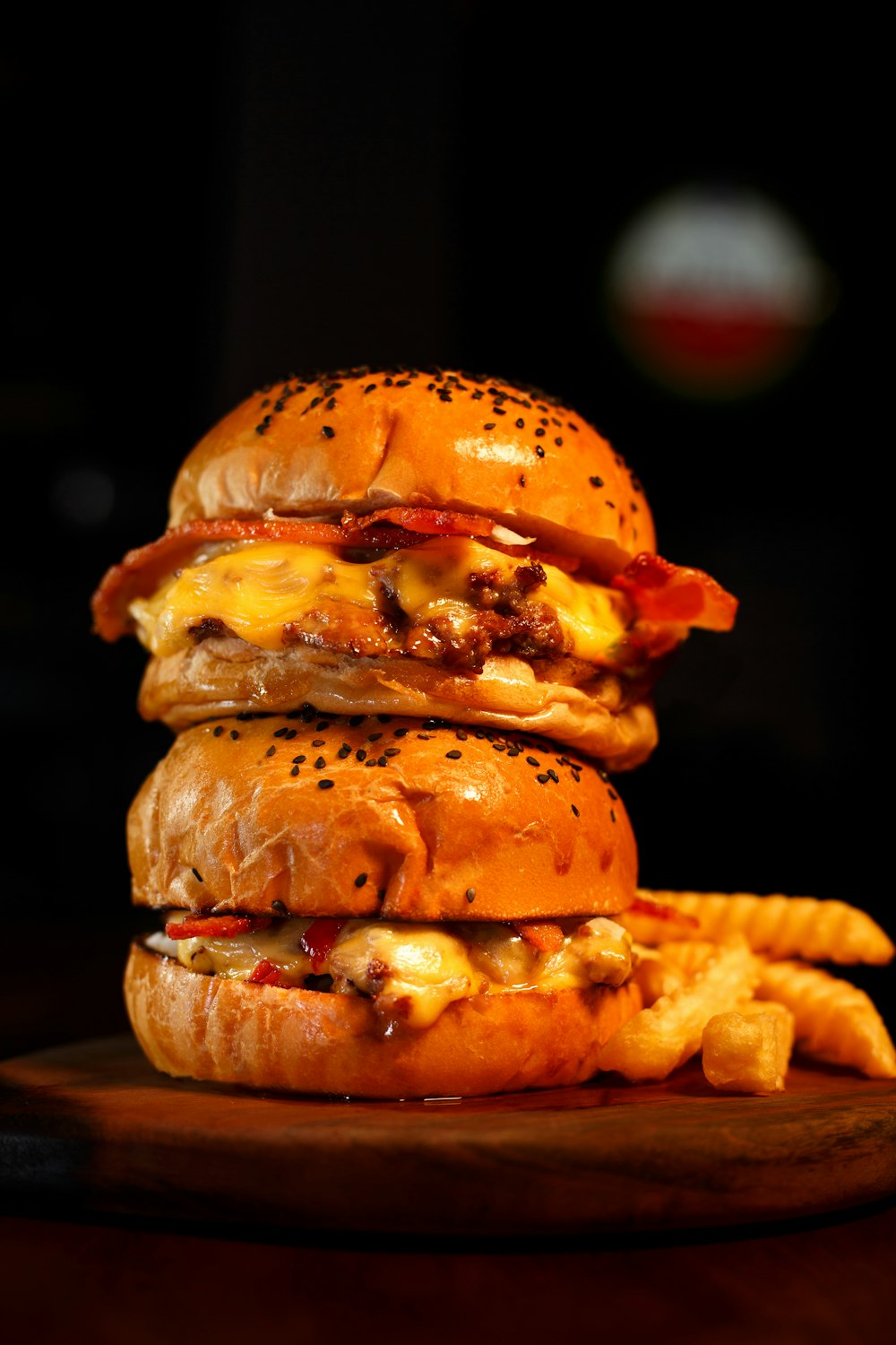 Una hamburguesa con queso y tocino con papas fritas en un plato de madera