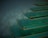 A series of elegant, translucent green steps with a glossy finish and golden edges, appearing to float against a misty, dark background. The design creates a sense of surrealism and futurism.