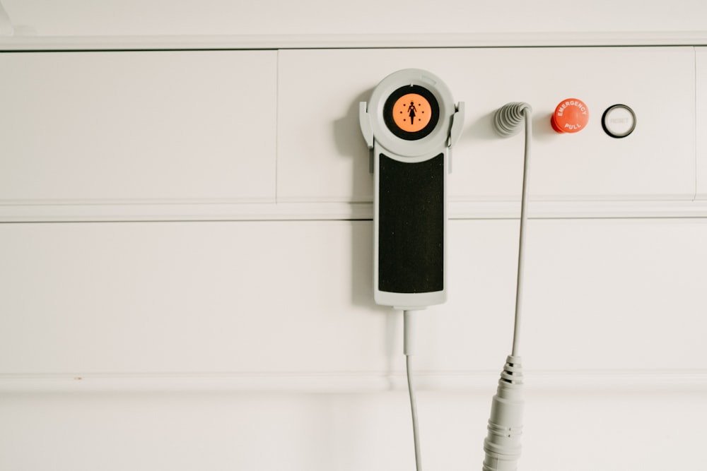 a white wall with a phone and two wires attached to it