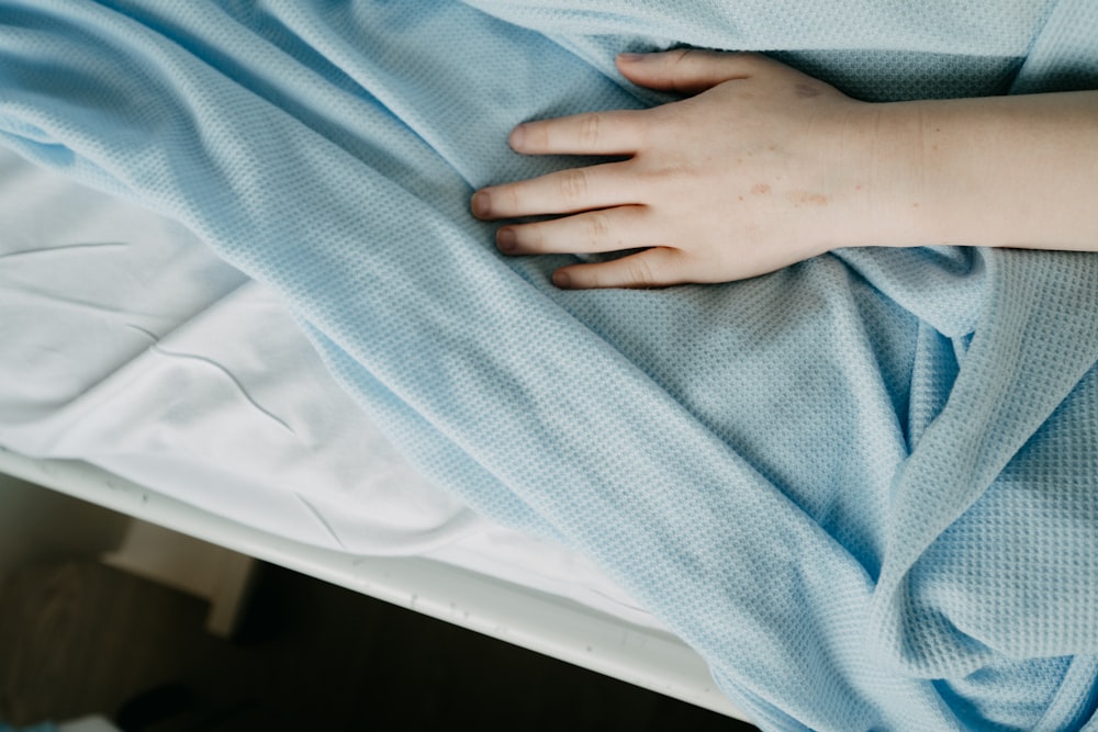 a person's hand resting on a blanket on a bed