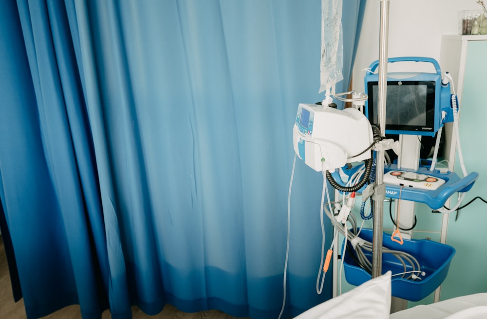 a hospital room with a blue curtain and a monitor