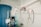 A hospital room with medical equipment, including an IV stand, a blood pressure monitor, a suction canister, and various medical instruments attached to a wall. The room features a blue privacy curtain and a shelf with medical supplies.