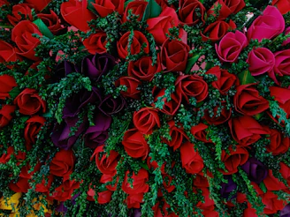 A luxurious floral arrangement featuring deep red roses and gold accents in a modern vase.