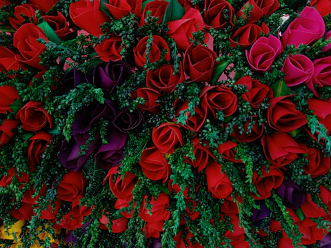 A luxurious floral arrangement featuring deep red roses and gold accents in a modern vase.