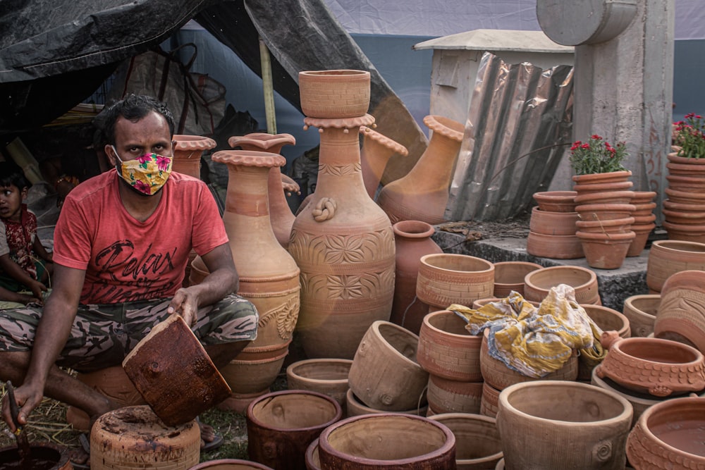 a man sitting in front of a pile of clay pots