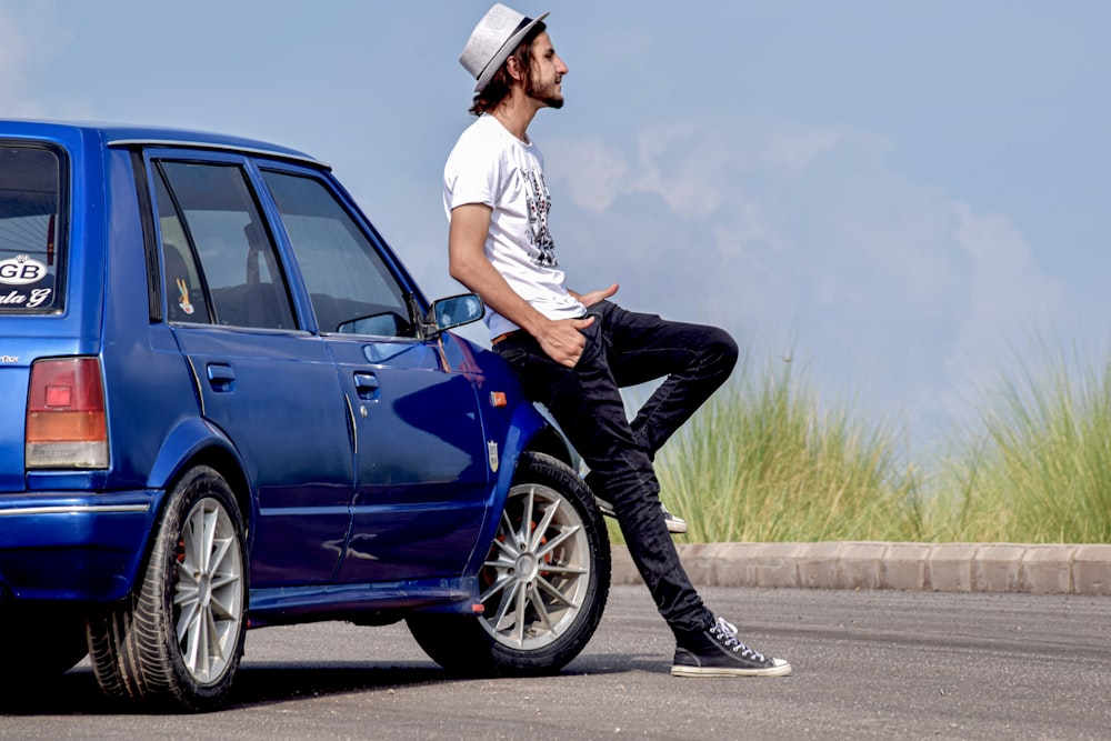 a man sitting on the hood of a blue car