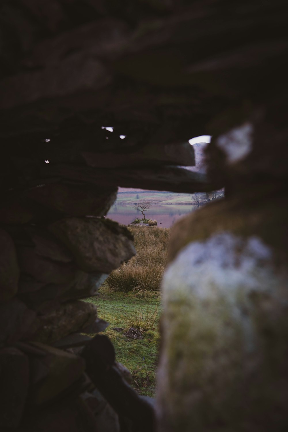 a view of a field through a stone wall