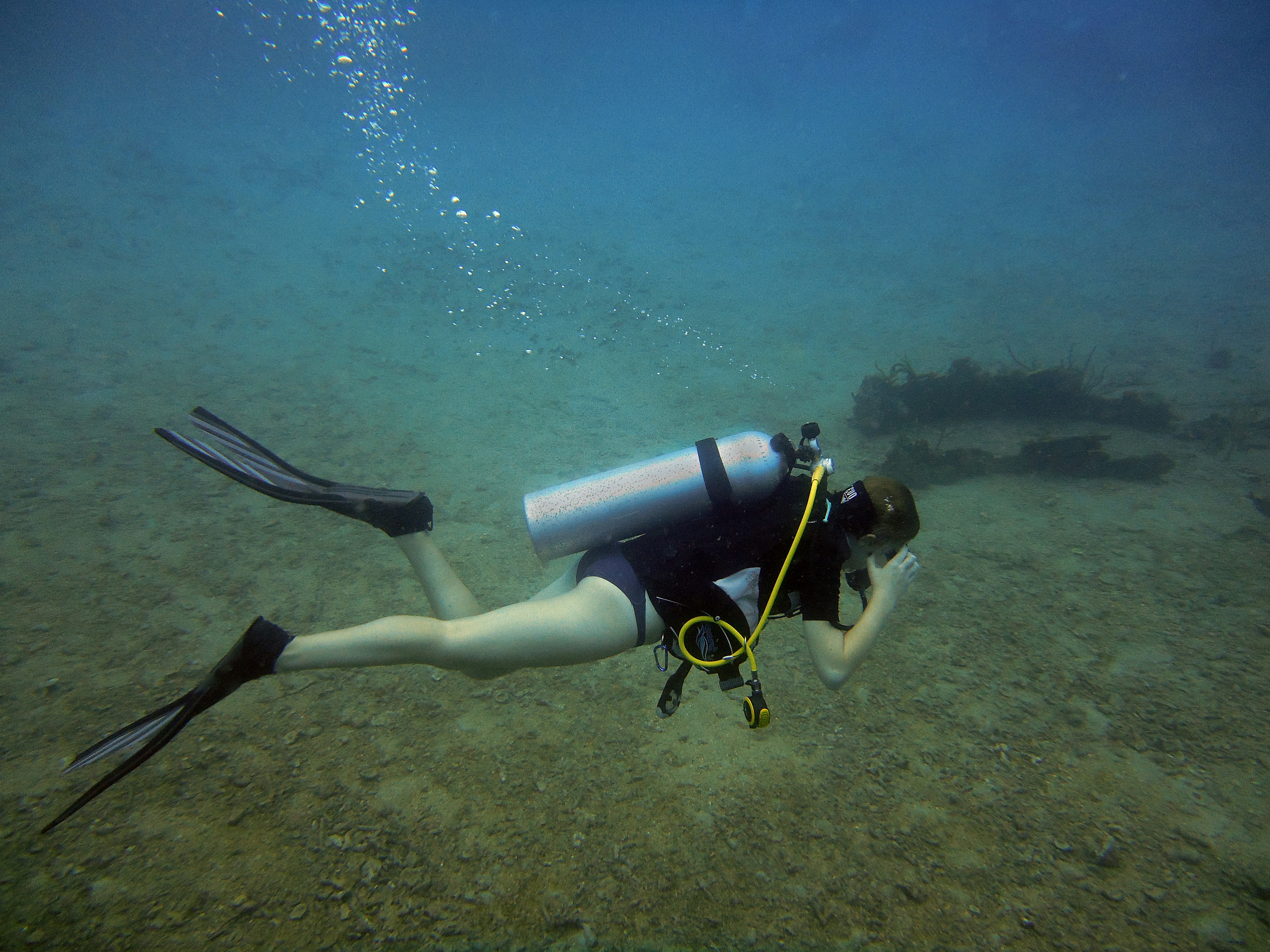 a woman scubas in the water with a scuba pole