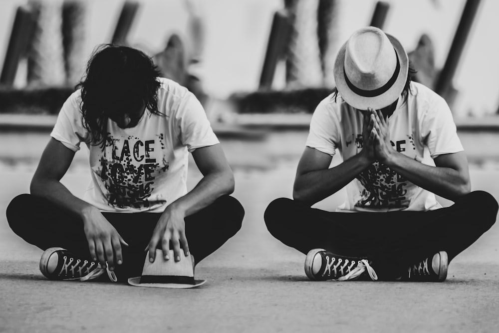 two people sitting on the ground with hats on