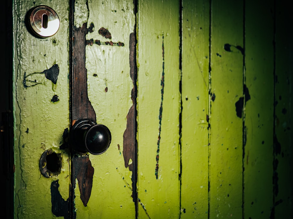 a close up of a door handle on a green door