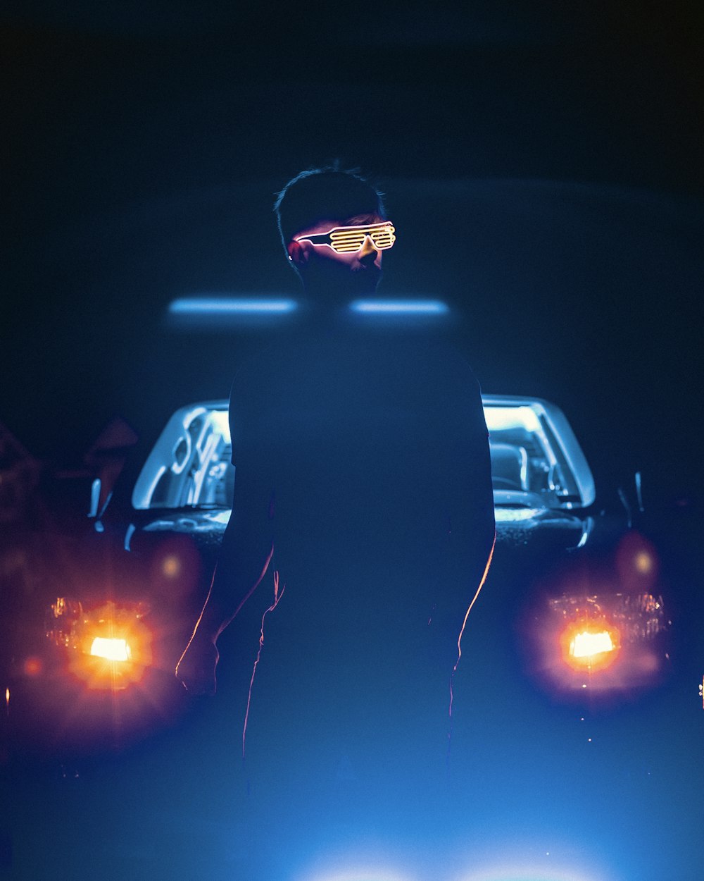 a man standing in front of a car at night