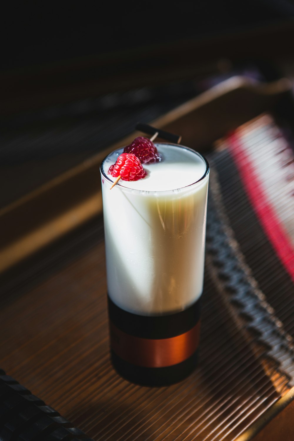 a glass of milk and a strawberry on a table