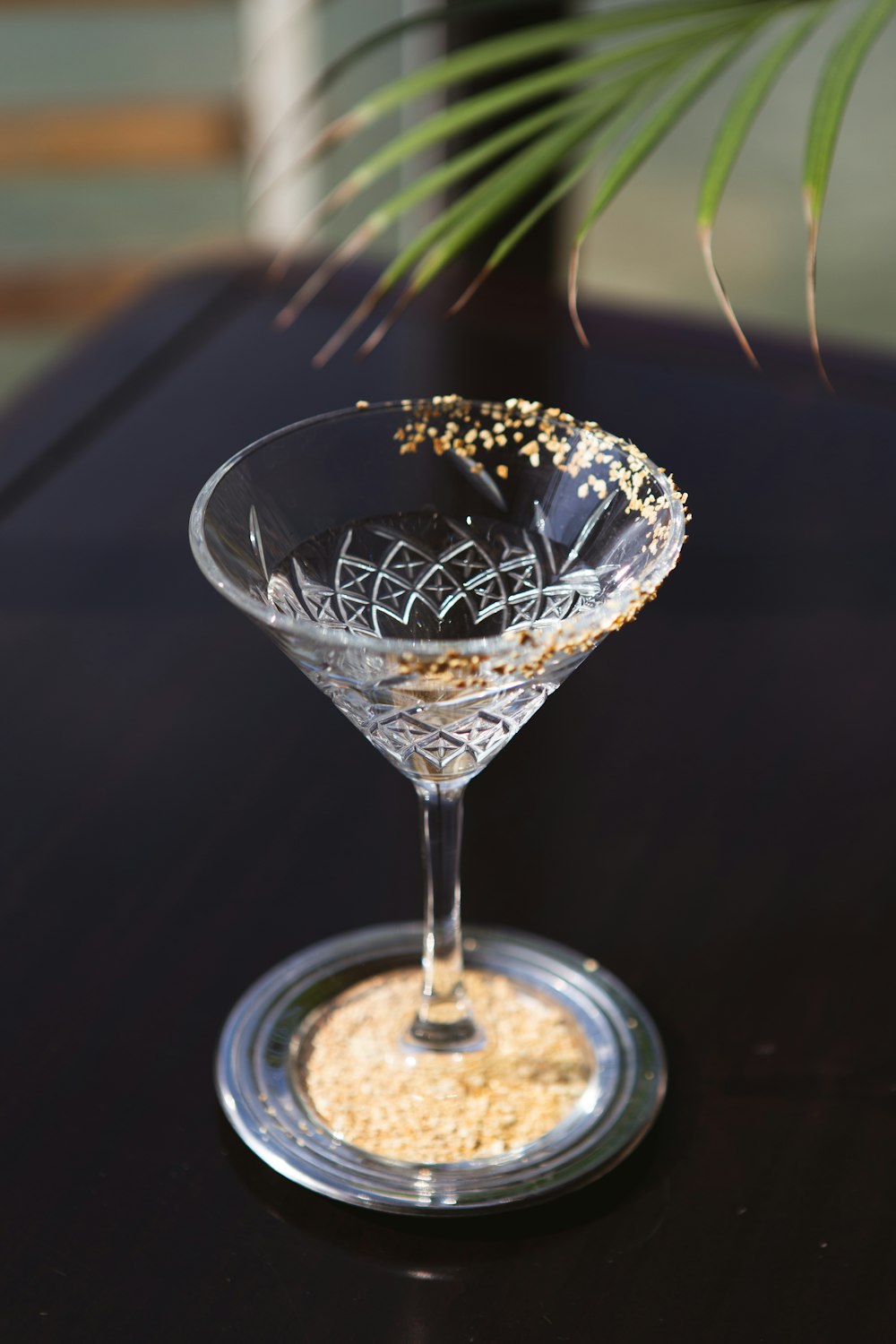 um copo de martini cheio de flocos de ouro em uma mesa preta
