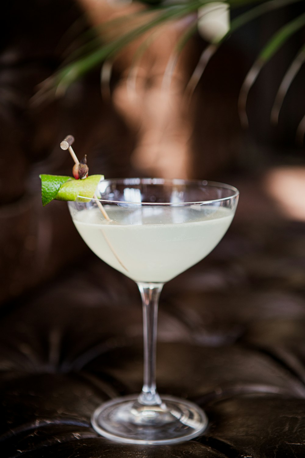 a white cocktail with a green garnish garnish in a glass