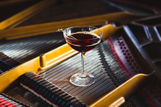 a glass of wine sitting on top of a piano