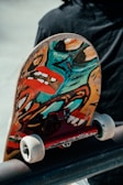 Close-up of a skateboard deck featuring vibrant cartoon graffiti art under bright sunlight.