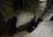 A person in formal attire is adjusting or wearing a brown leather shoe. The setting appears to be indoors, with a focus on well-tailored trousers and a white long-sleeved shirt.
