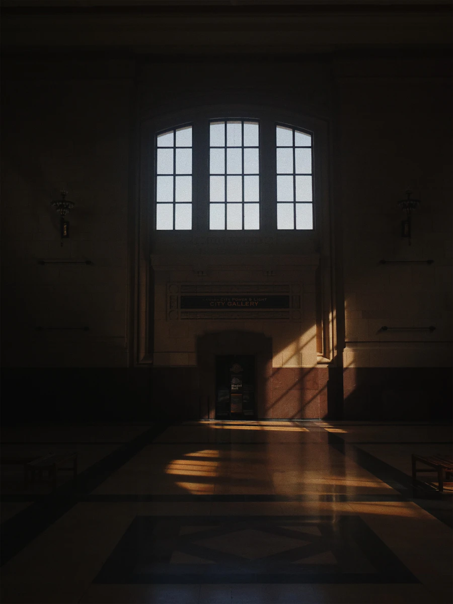 Grand stone hall with a tall window and soft pooling light (placeholder photograph)