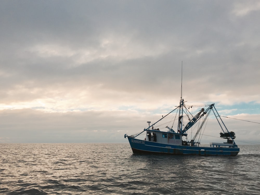 a blue and white boat floating on top of a body of water