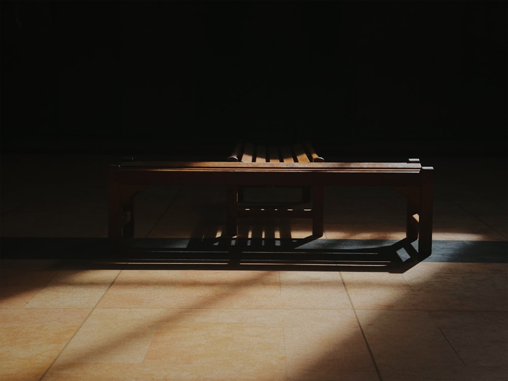 a wooden bench sitting on top of a tiled floor