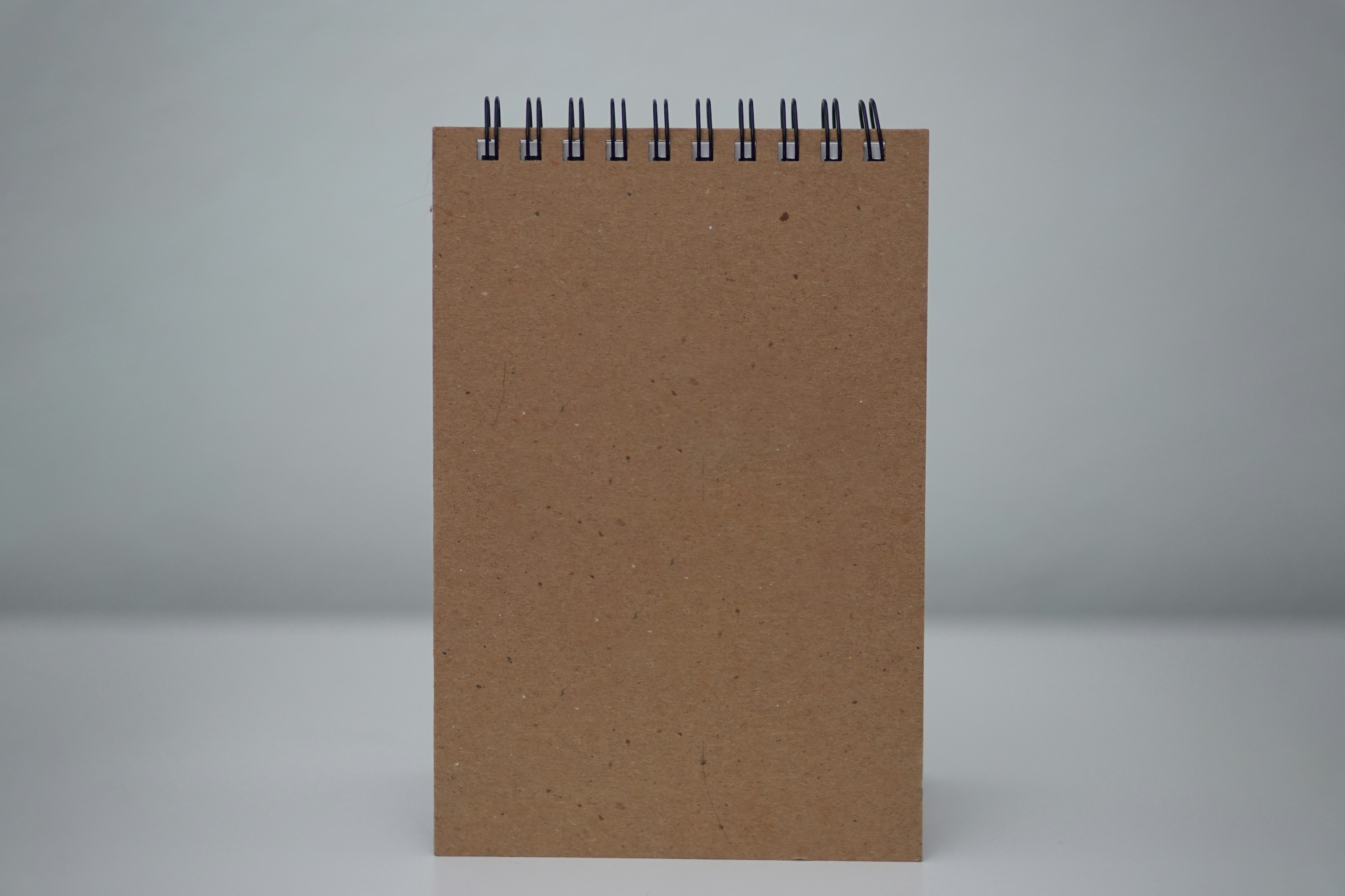 A spiral notebook with a brown cover on a white background