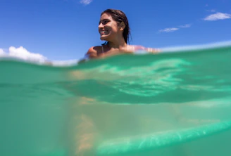 a woman swimming in the ocean under a blue sky