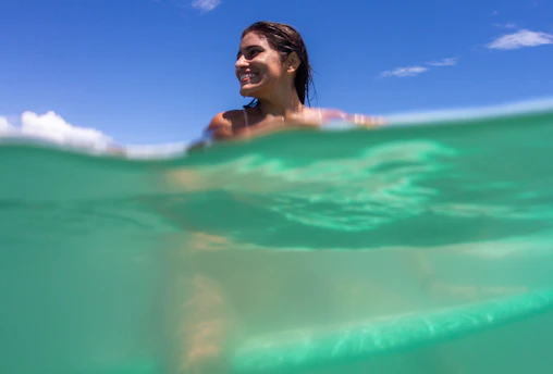 a woman swimming in the ocean under a blue sky
