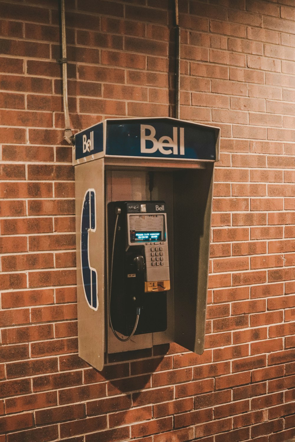 an old style pay phone in front of a brick wall