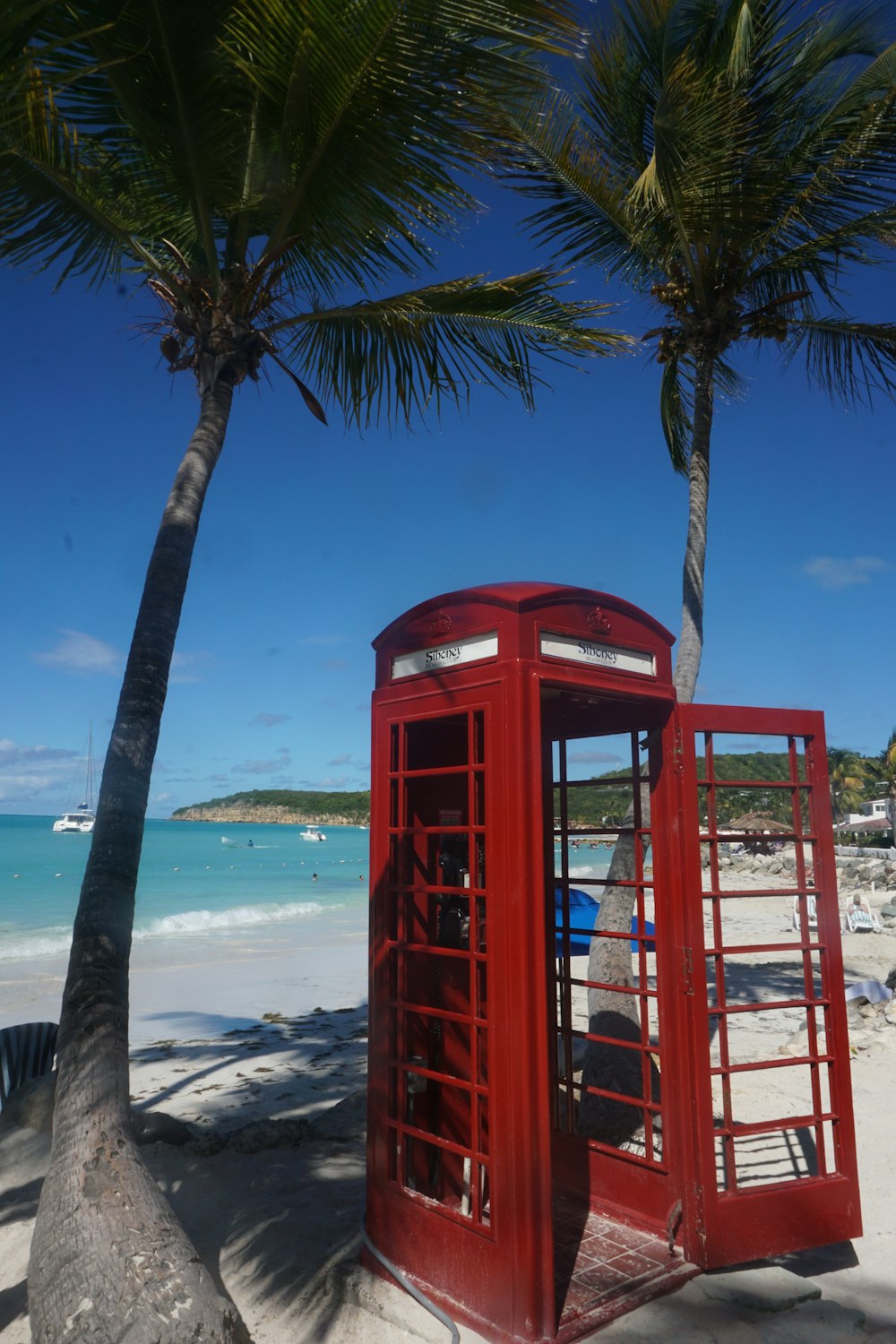 Una cabina telefónica roja sentada en la parte superior de una playa de arena