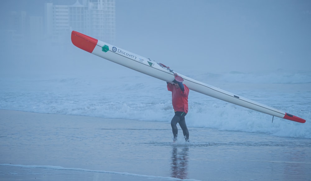a man carrying a surfboard across a wet beach