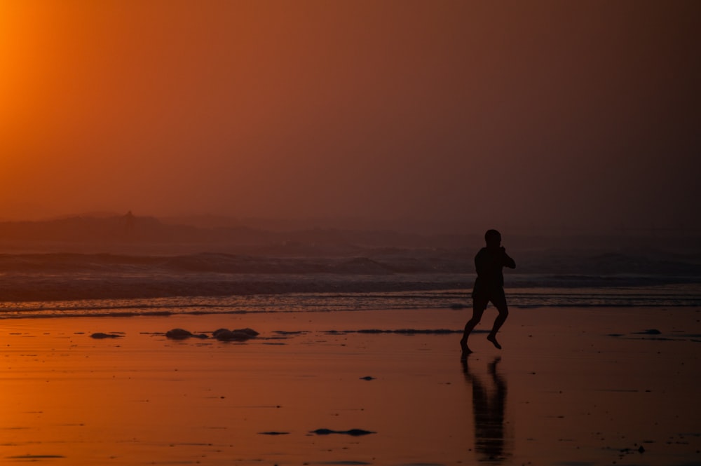 a person running on a beach at sunset