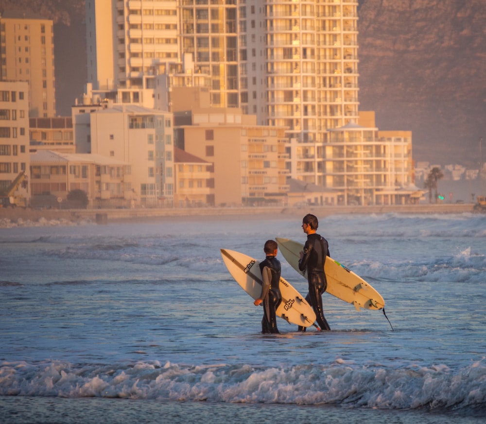 two surfers carrying their surfboards into the ocean