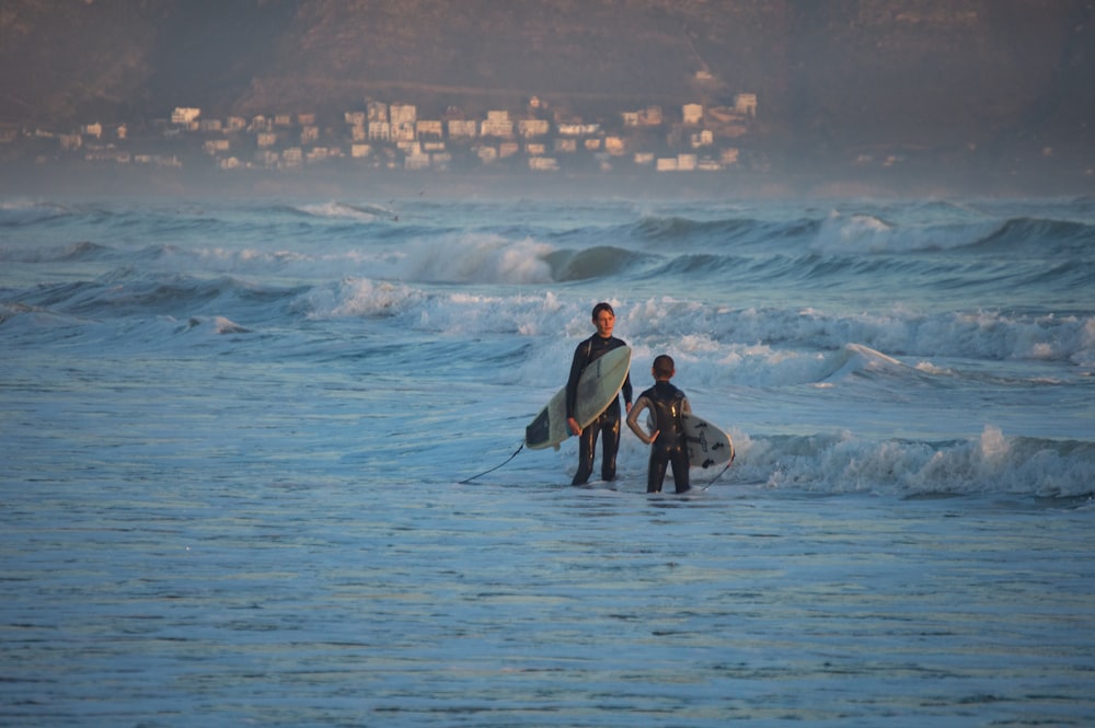 a man and a child holding surfboards in the ocean