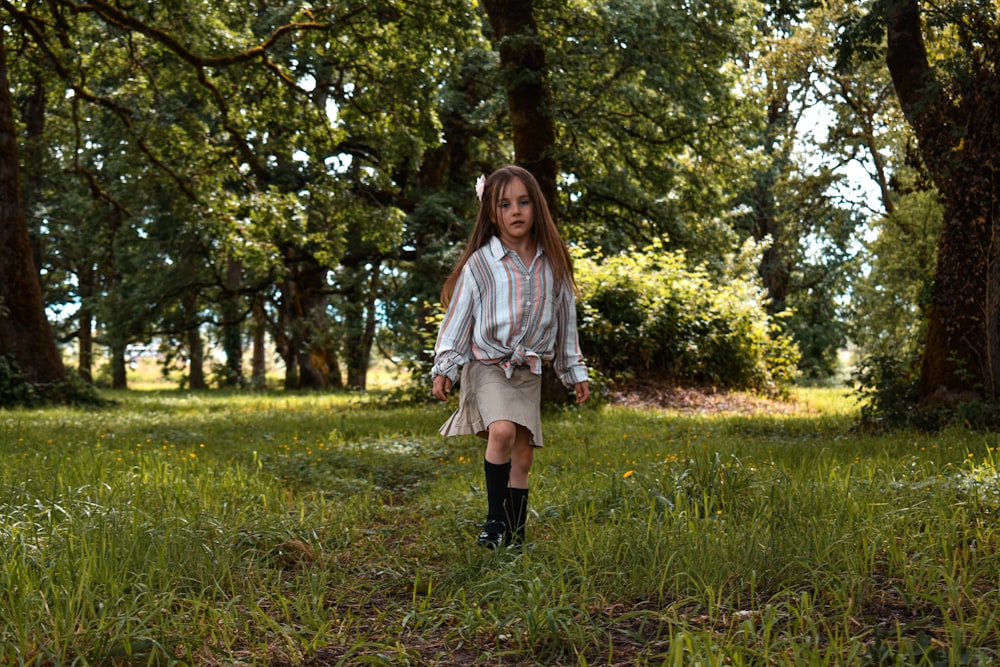 a little girl walking through a field of grass