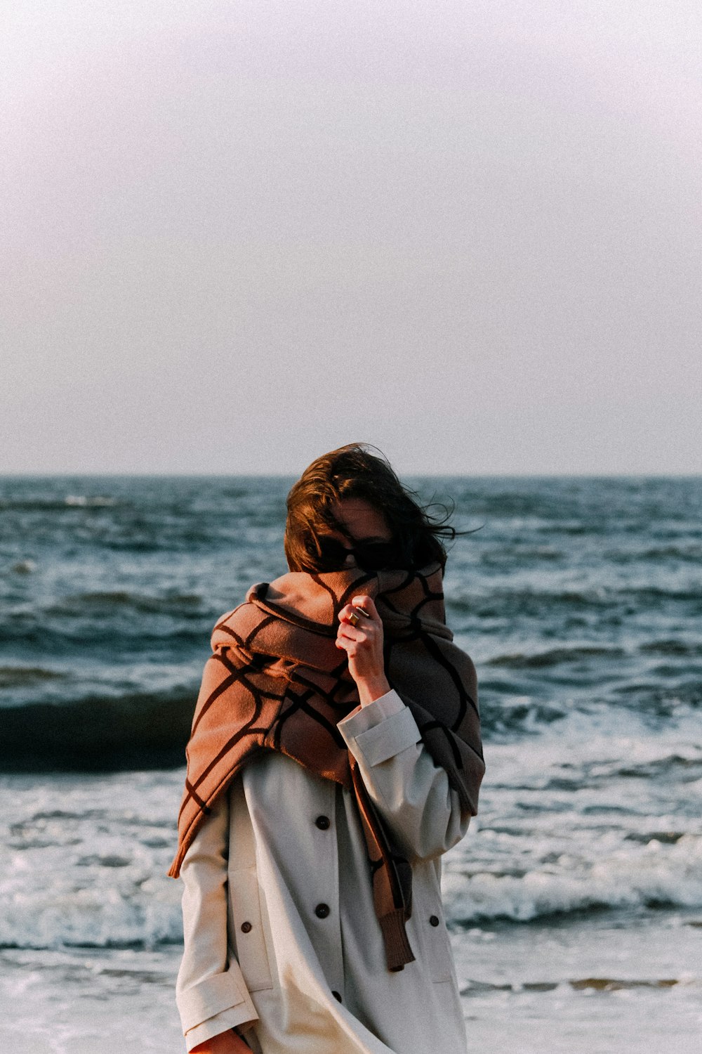 Une femme debout au sommet d’une plage au bord de l’océan