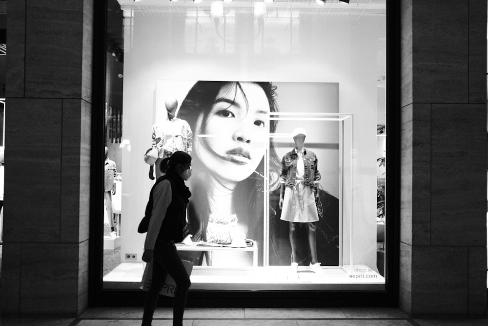 a woman is walking past a window display