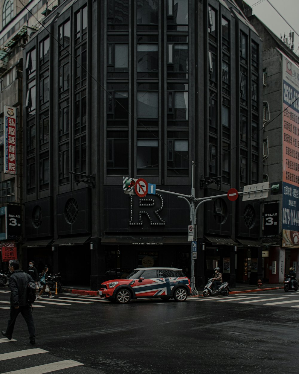 a red car driving down a street next to tall buildings