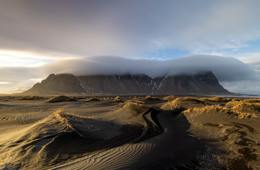 a large mountain covered in clouds and sand